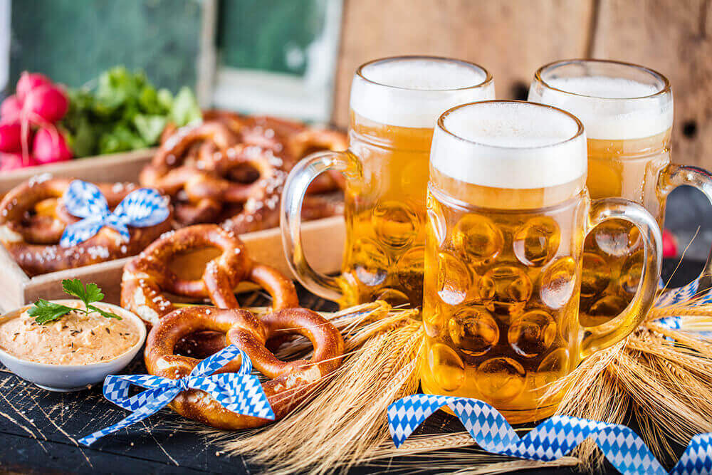 canecas de cerveja e comidas típicas da Alemanha representando como organizar uma oktoberfest