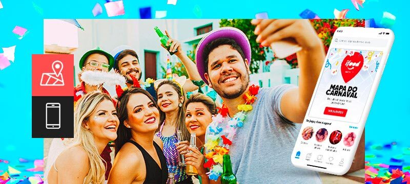 A imagem mostra um grupo de amigos posando para uma foto em um bloquinho de Carnaval. Eles usam adereços festivos. Há um celular mostrando o app da Sympla com o Mapa do Carnaval 2023.