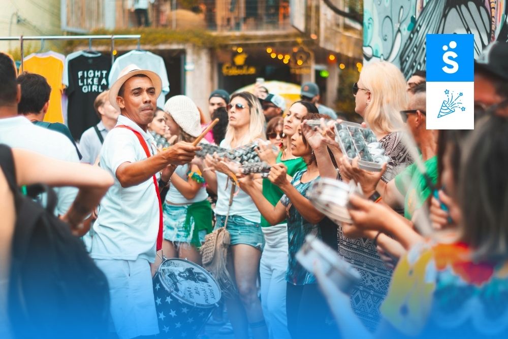 Pessoas celebram ao redor de um homem que toca instrumento de sopro no Carnaval de BH.